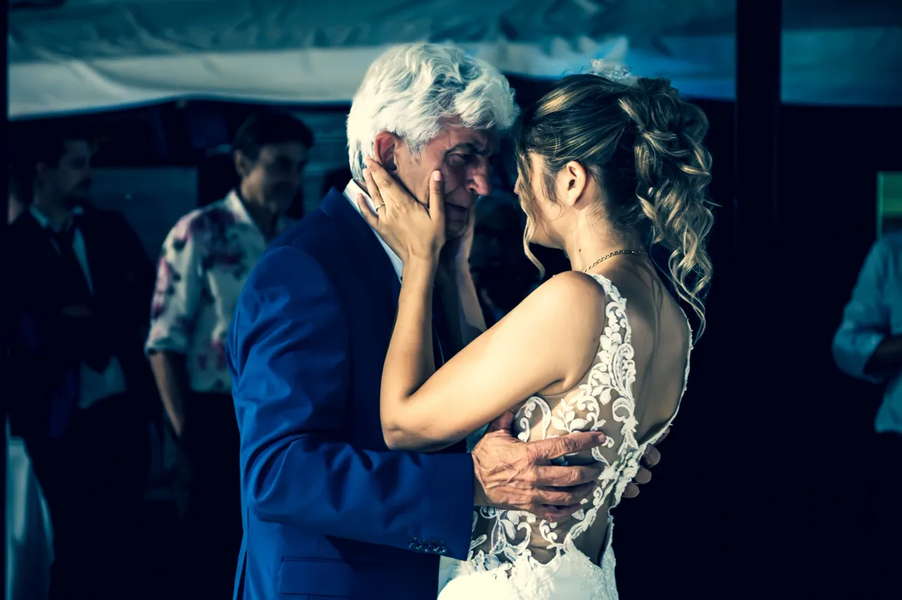 A man and the bride touching each other’s faces during a dance