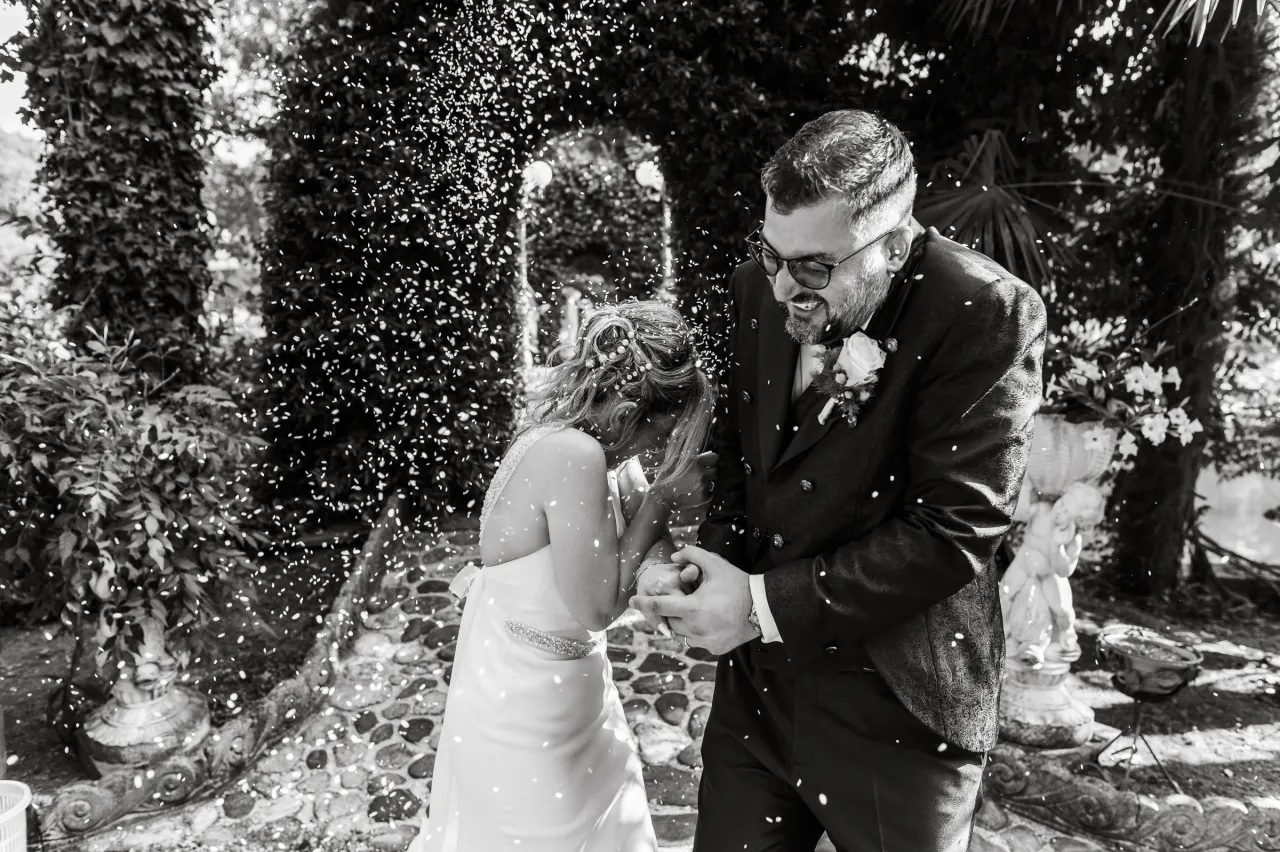 The couple smiling as rice is thrown