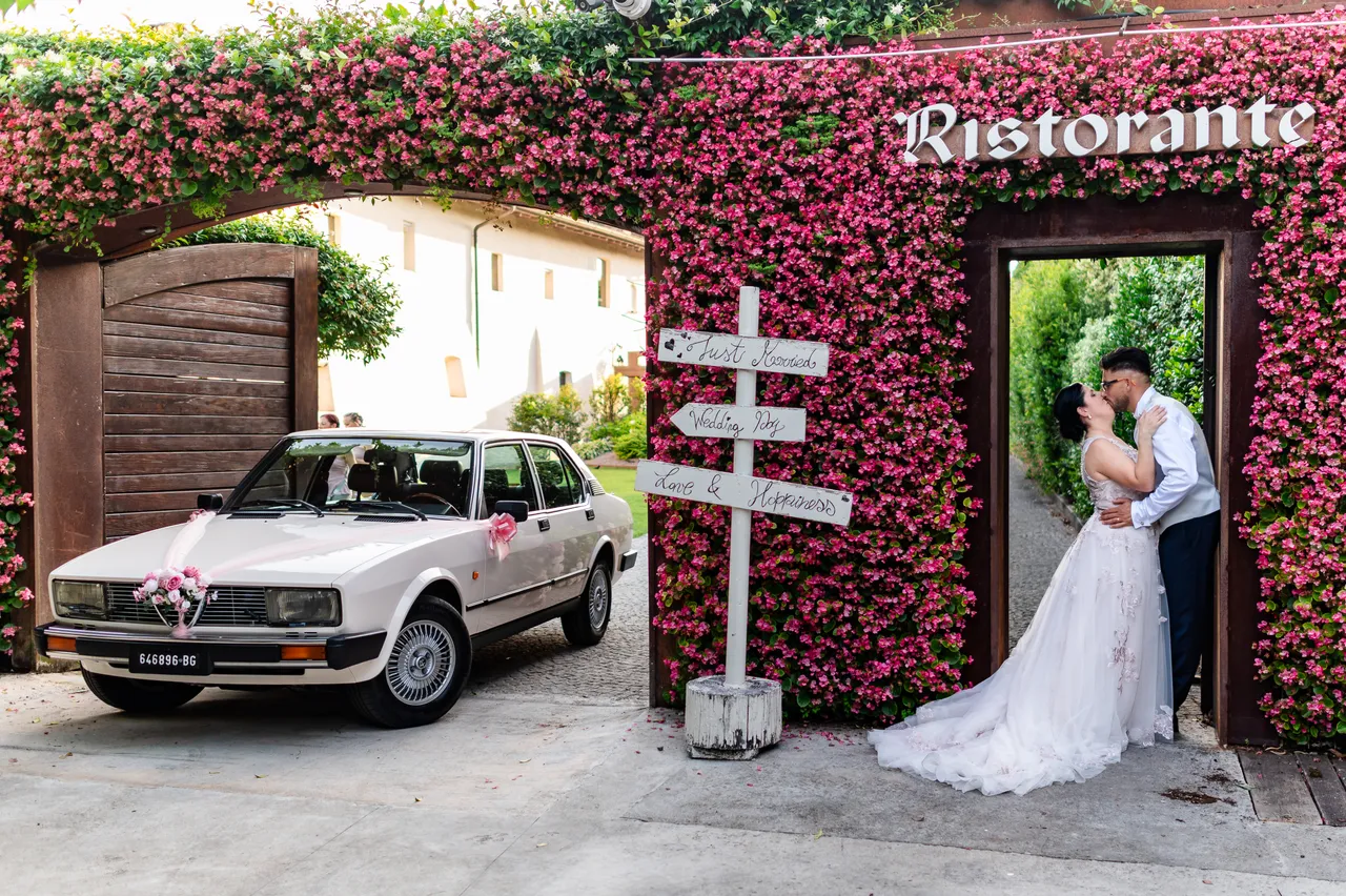 Alessandra and Gianluca kissing at the flower-covered entrance of Convento dei Neveri