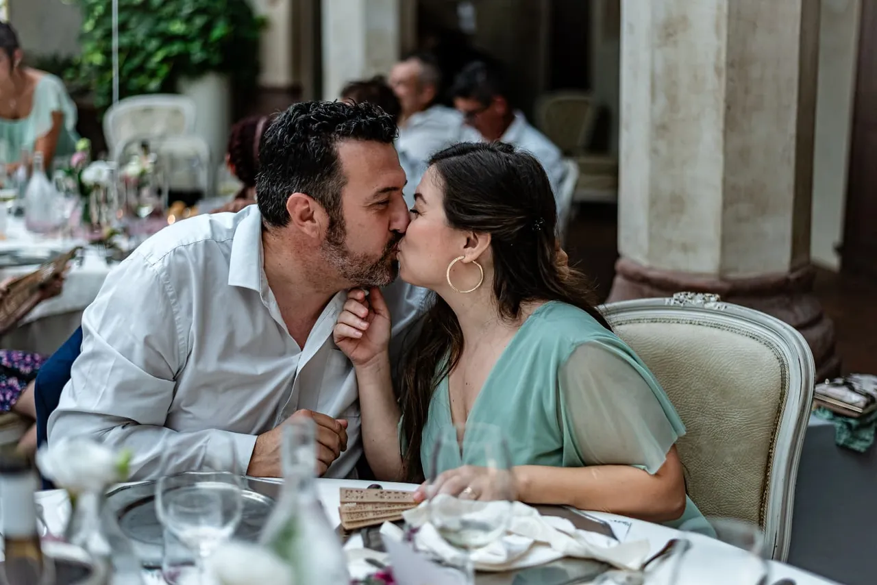 Due invitati si baciano a tavola durante il ricevimento