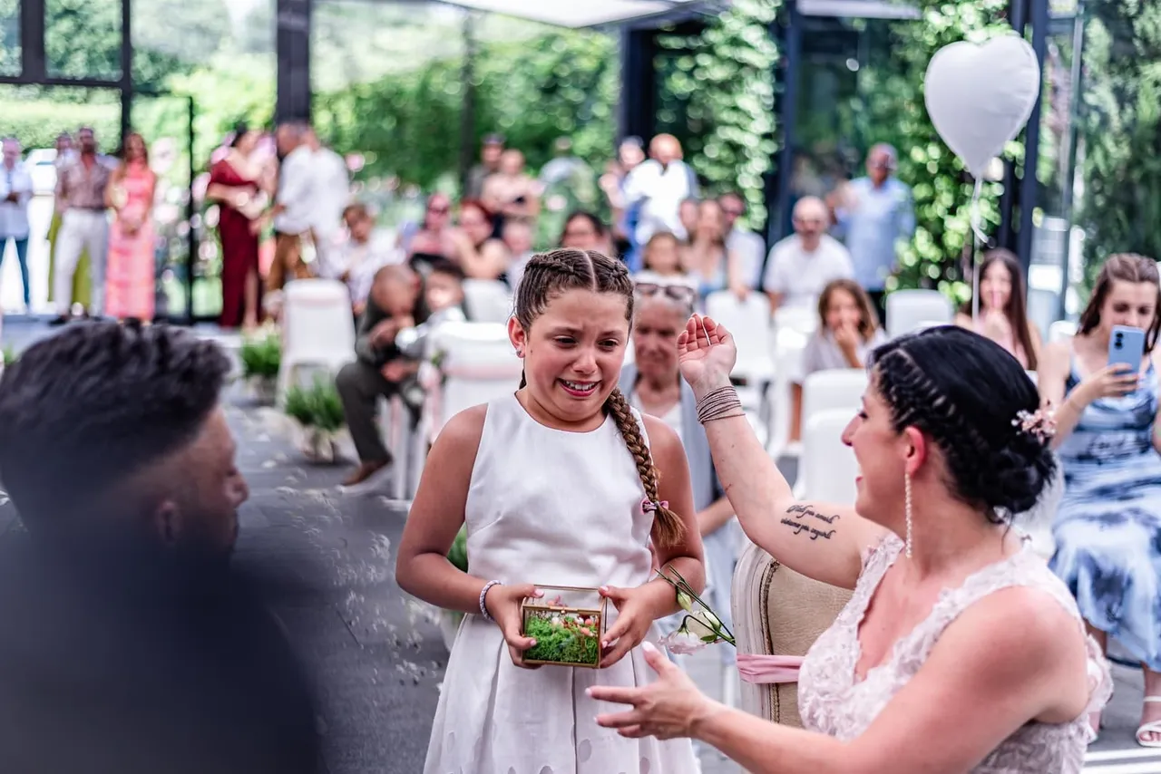 Una bambina porge il cuscino delle fedi alla sposa