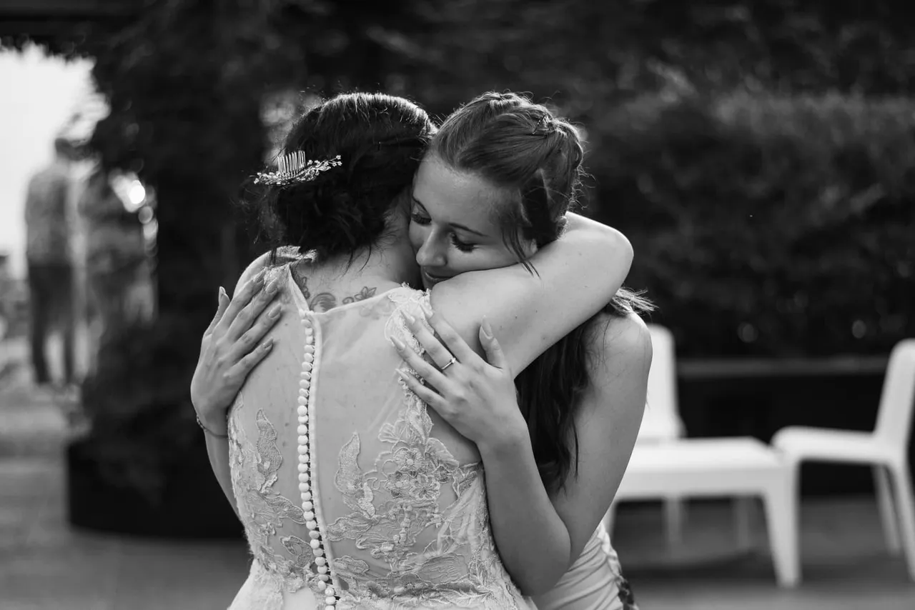 Alessandra embracing a young girl outdoors, in black and white