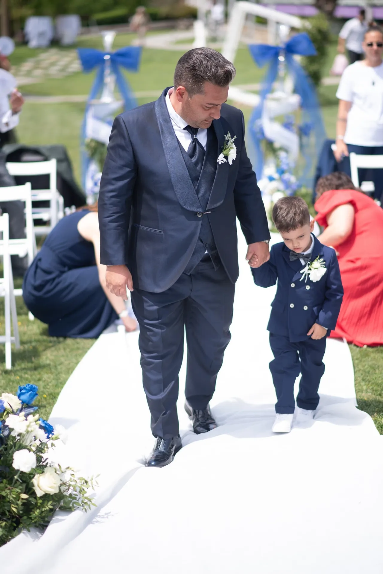 Lo sposo cammina con un bambino tra le sedie della cerimonia