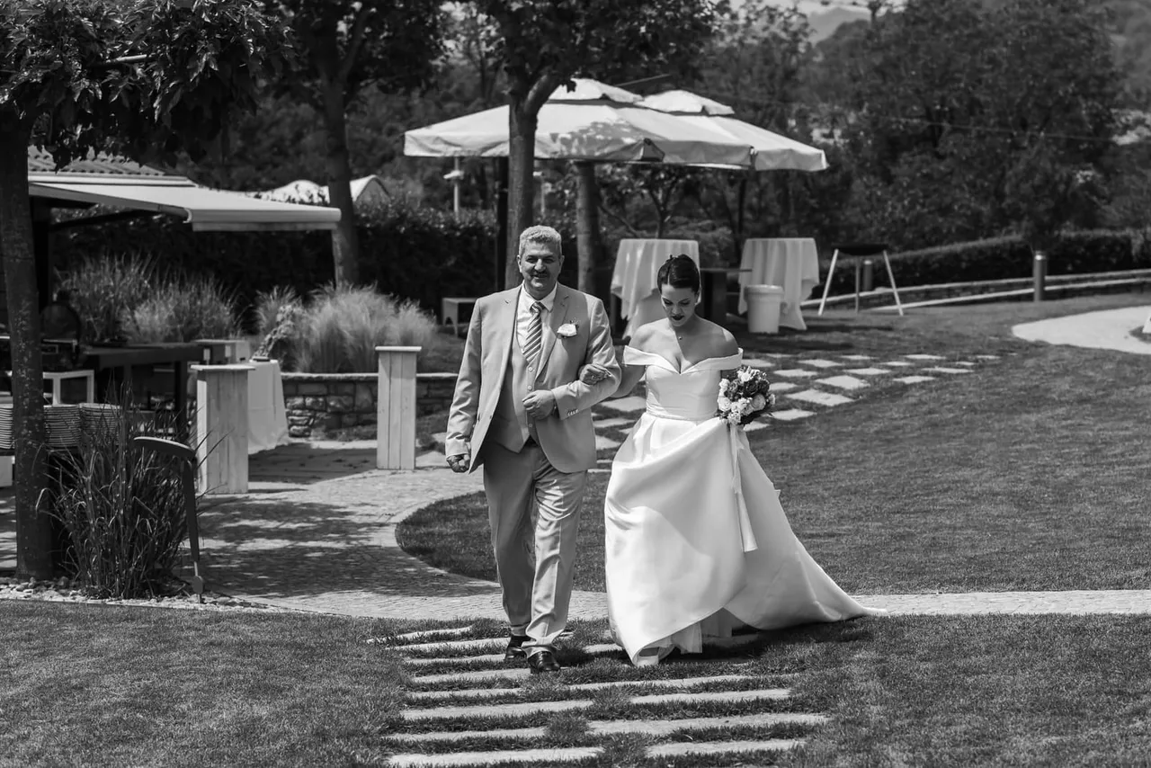 La sposa cammina a braccetto con un uomo, in bianco e nero
