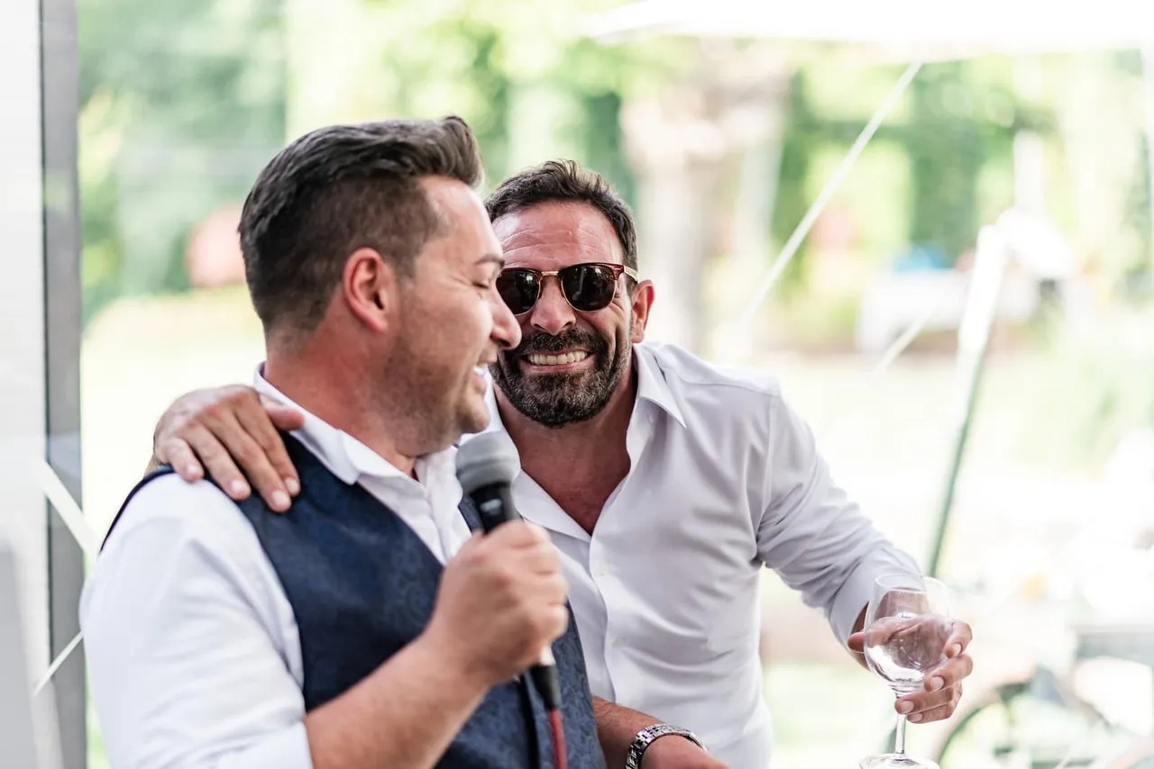 Lo sposo tiene il microfono accanto a un invitato