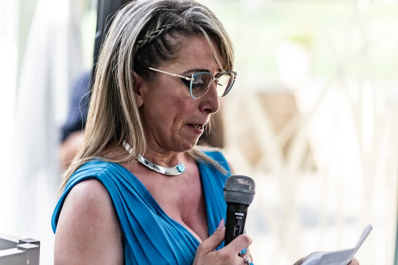 Daniela, testimone di Laura, legge il suo discorso al microfono con un abito azzurro