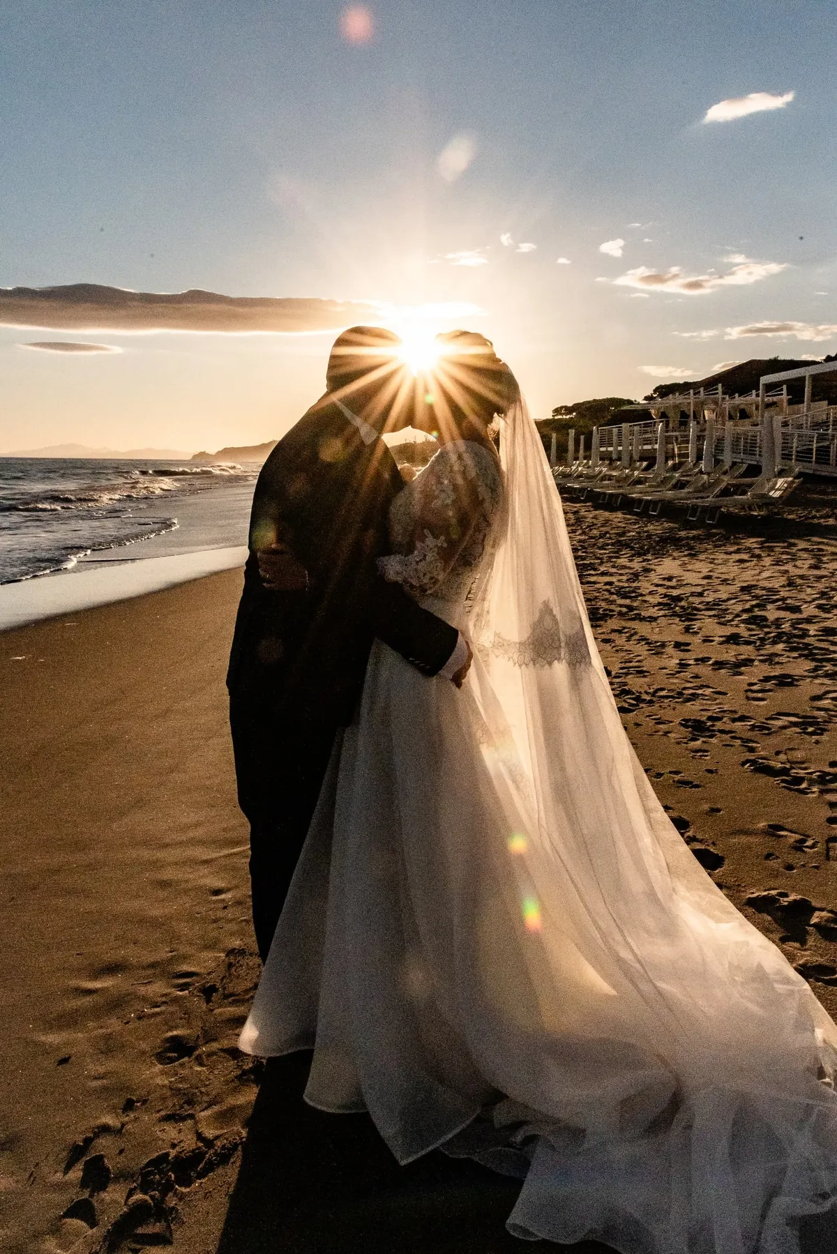 Valentina e Christian si baciano in controluce, con il velo illuminato