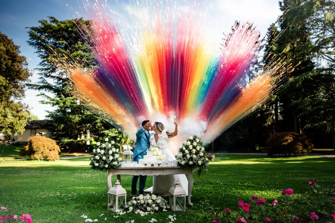 A couple toasting beneath a cascade of colours; a photograph, not a film still