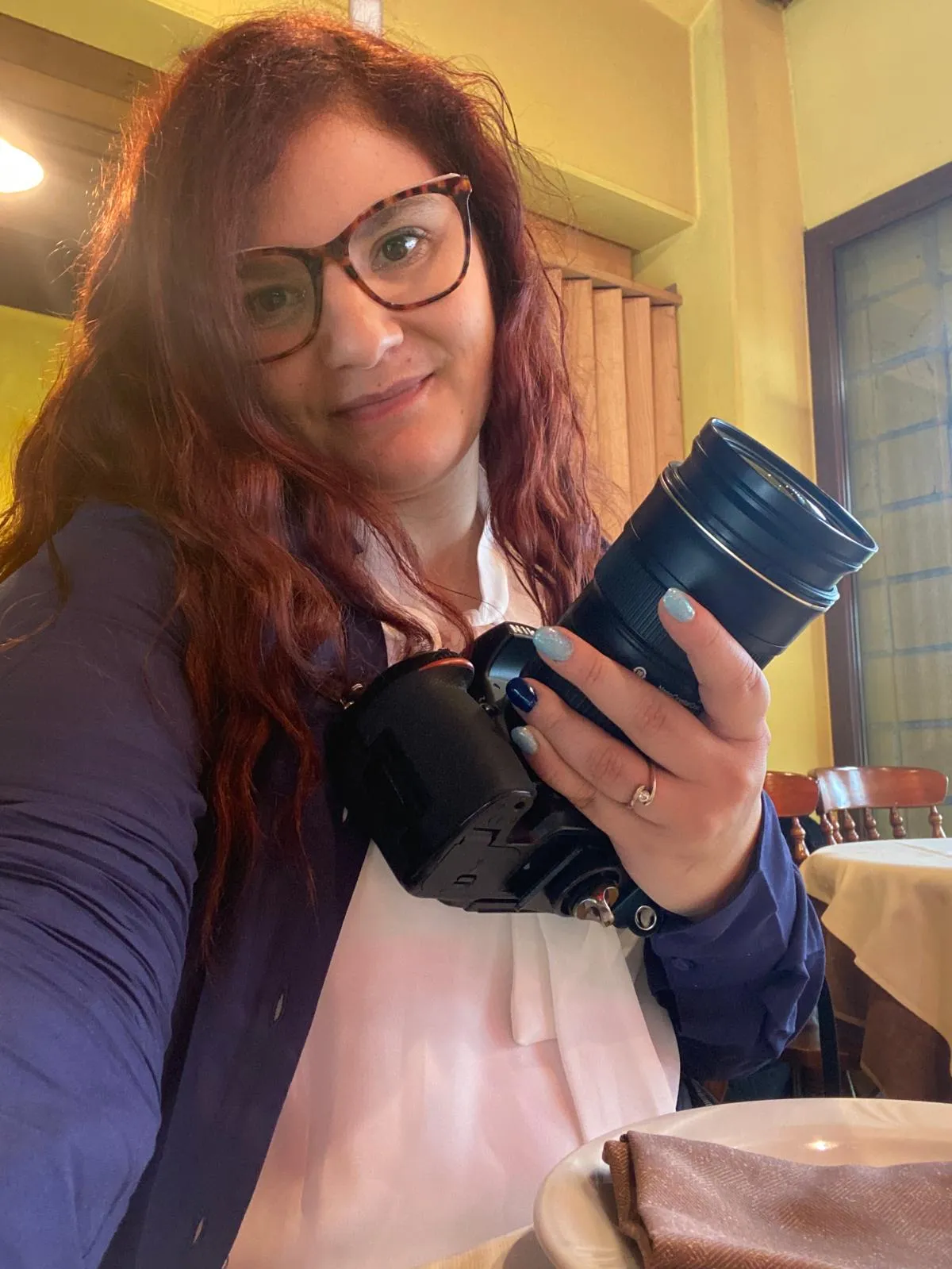 Jessica con gli occhiali e una fotocamera con teleobiettivo in mano