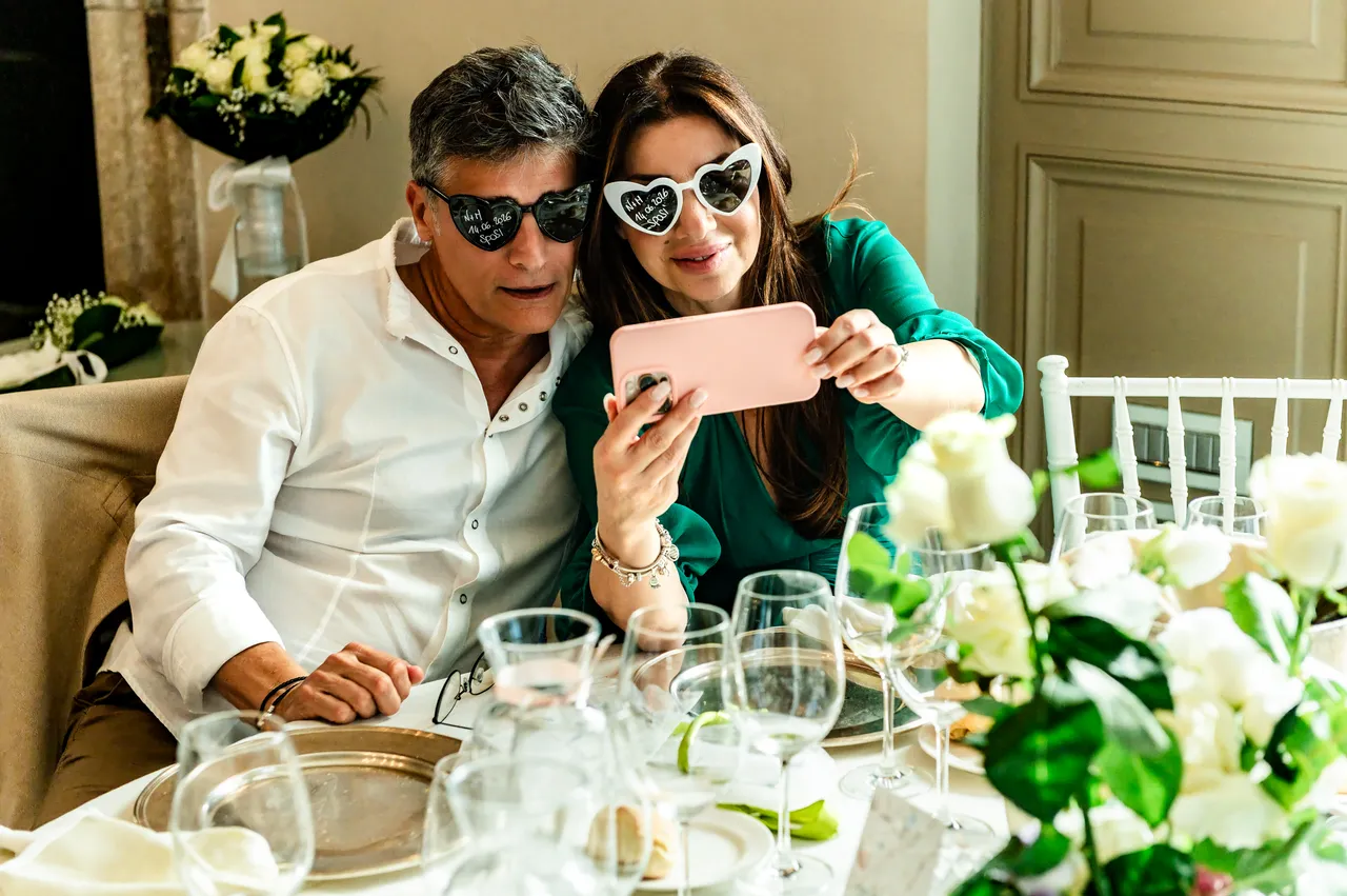 Due invitati si fotografano insieme a tavola con occhiali a cuore