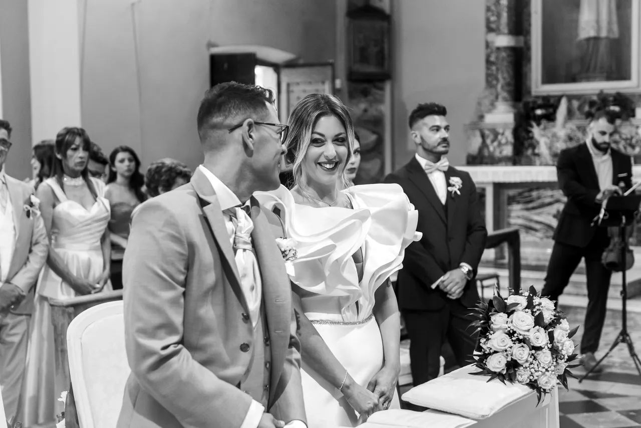 Nikla and Maurizio smiling at each other in church